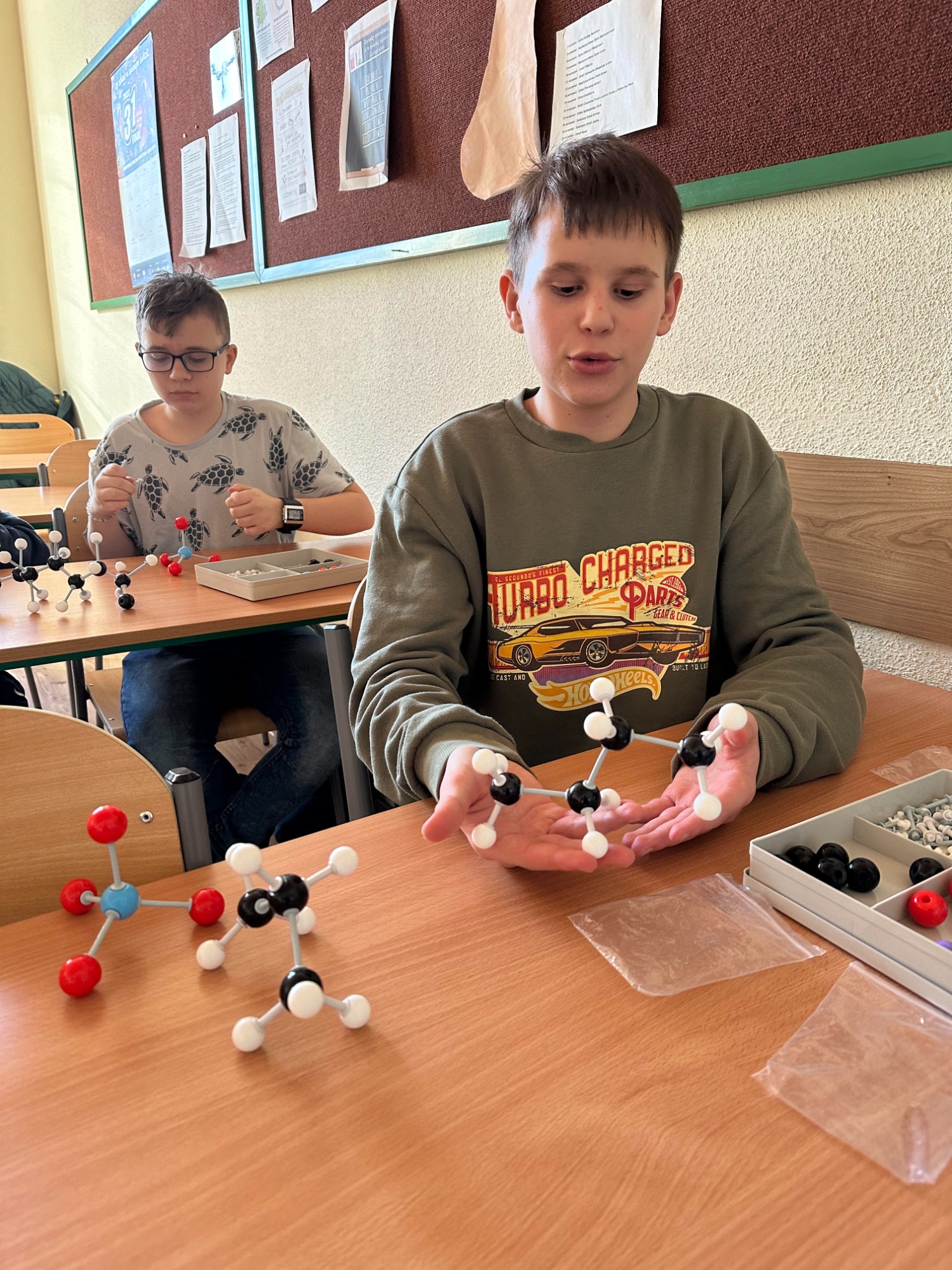 Chłopiec w klasie stworzył kolorowe modele cząsteczki. 