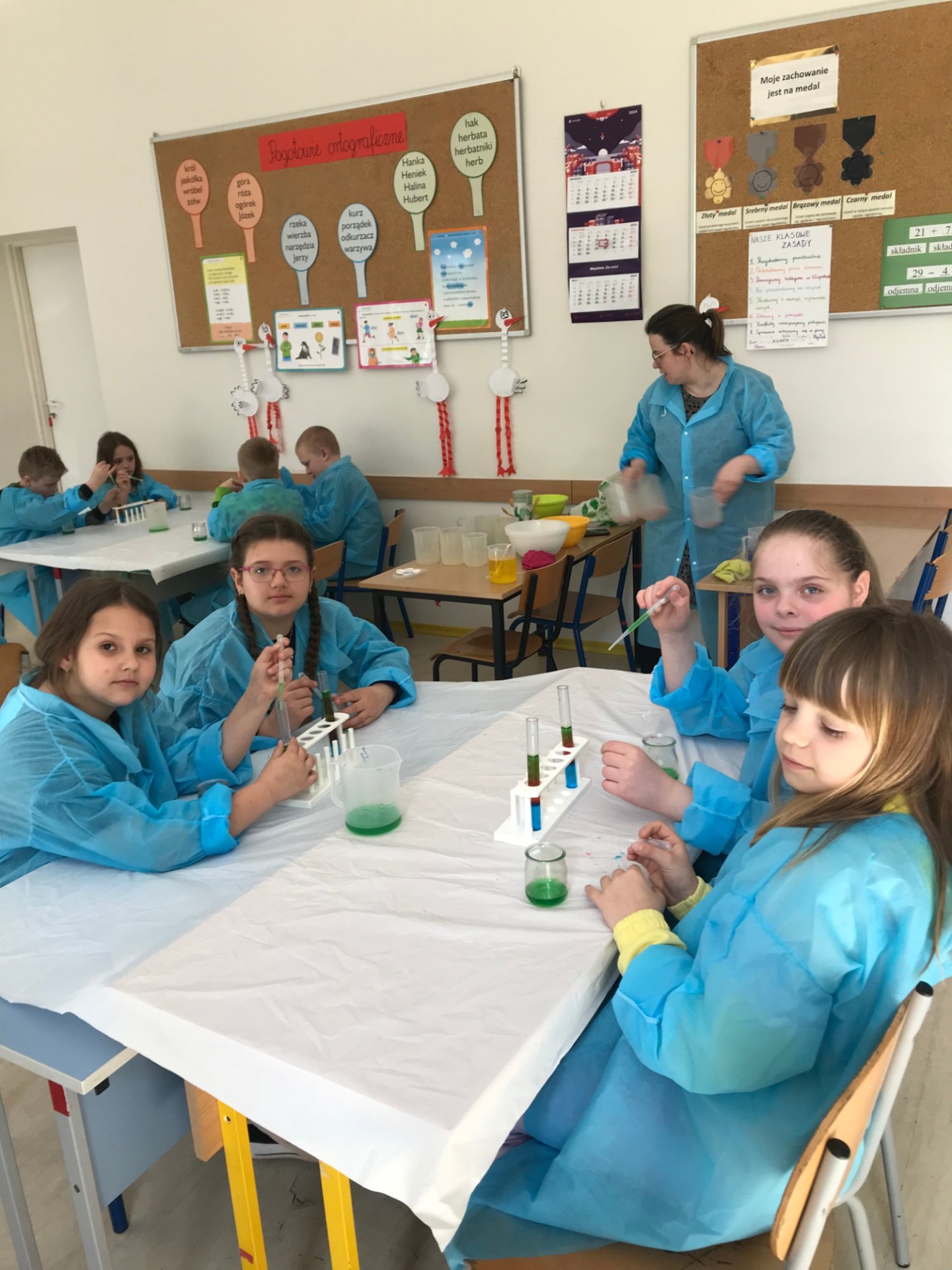 Grupa dzieci przy stolikach podczas eksperymentów
