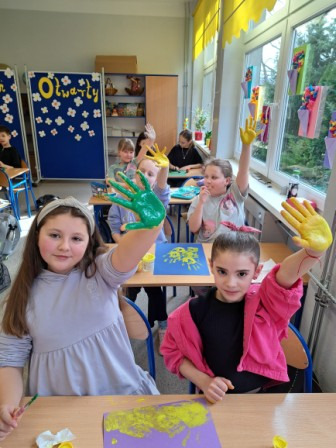 Uczniowie wykonujący pracę plastyczną dłońmi