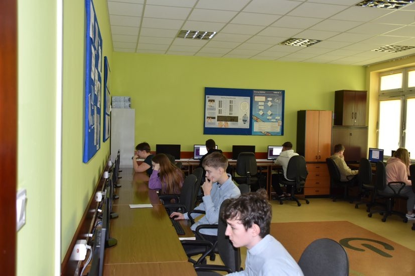 Uczniowie przy stanowiskach komputerowych w pracowni informatycznej wypełniają test konkursowy