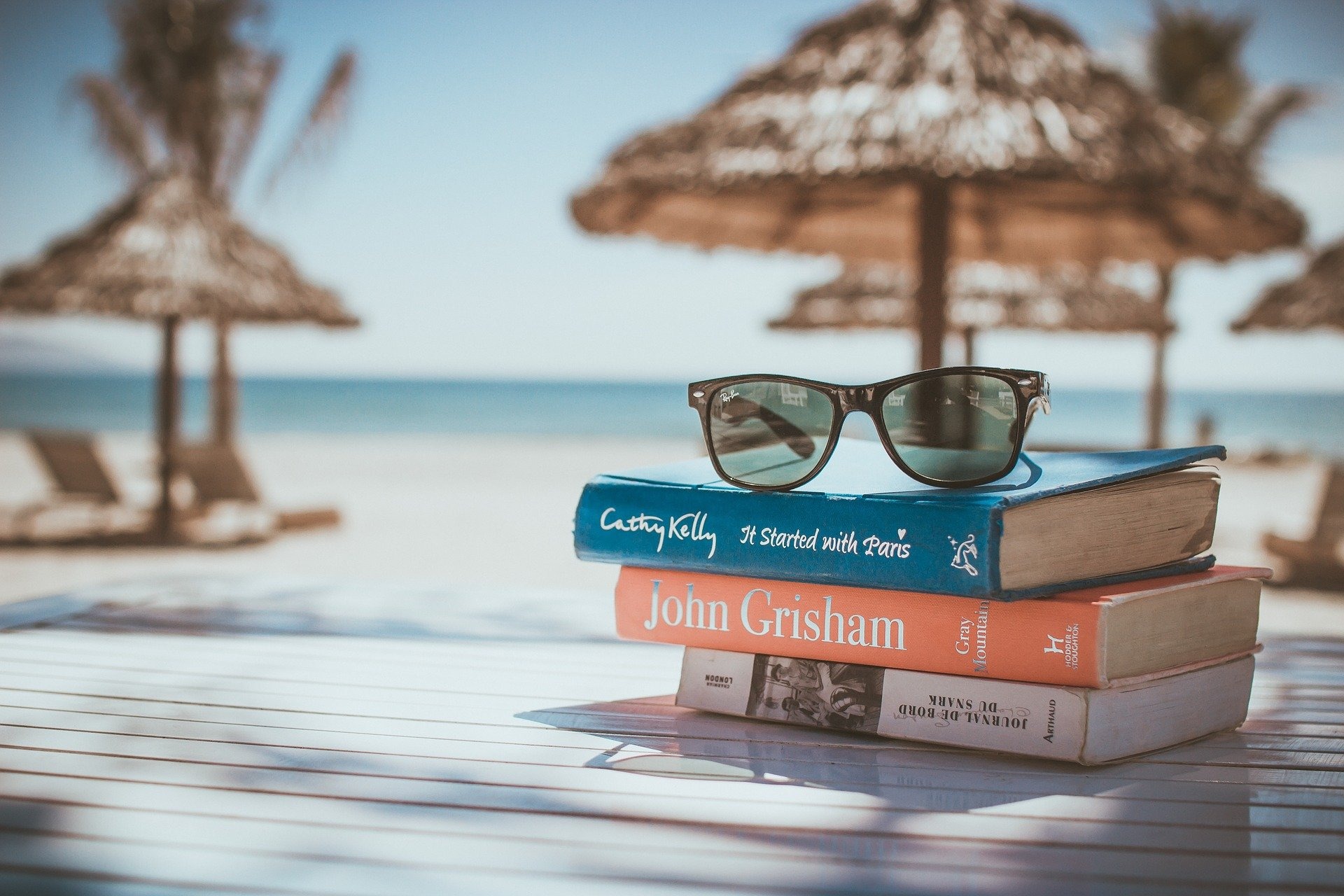 Obrazek przedstawiający książki, które leżą na plaży