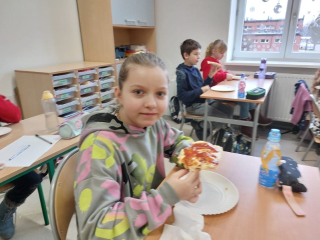 Uczniowie jedzący pizzę.