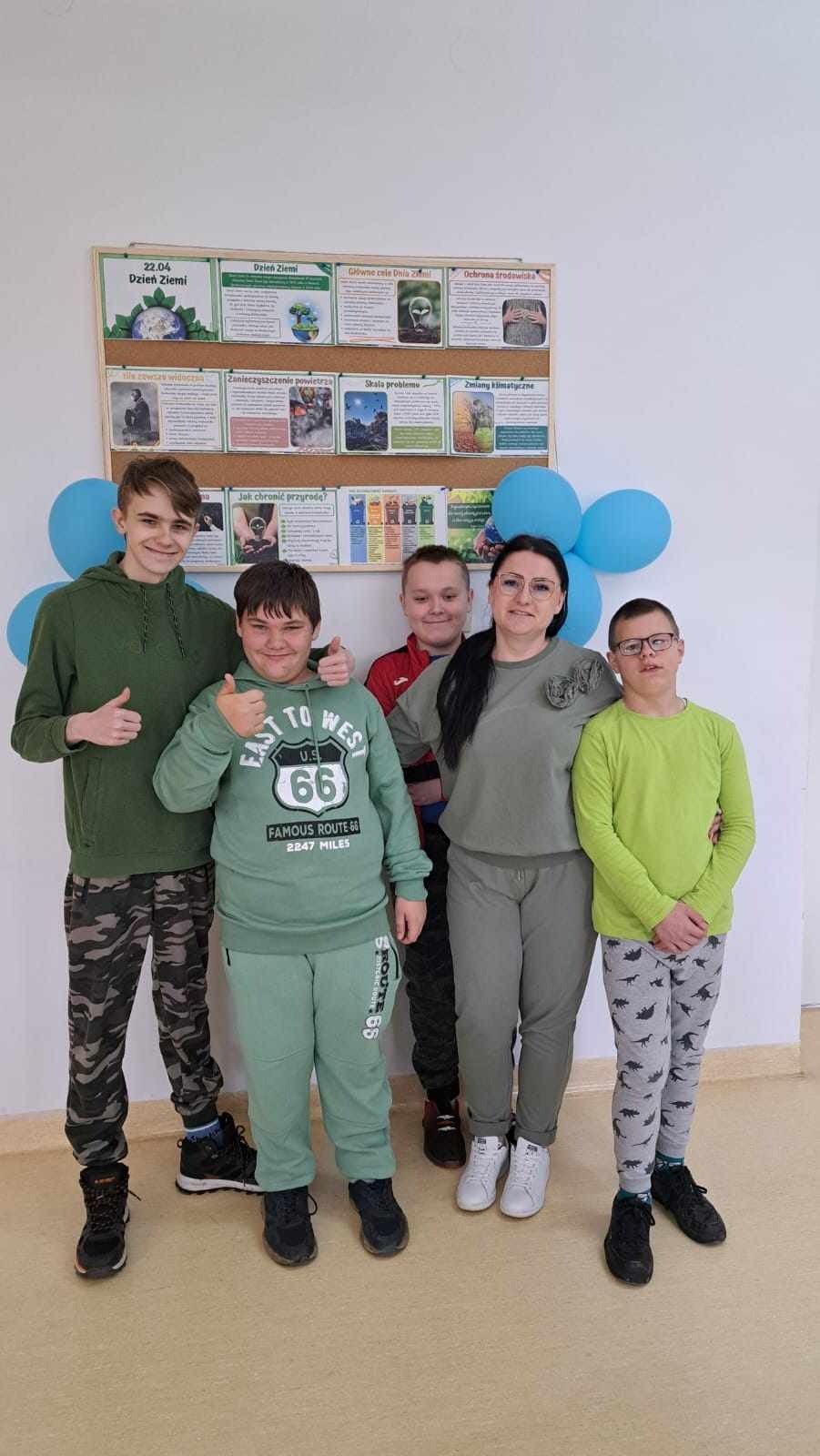 Grupa uczniów z wychowawcą pozuje do zdjęcia, są ubrani na zielono