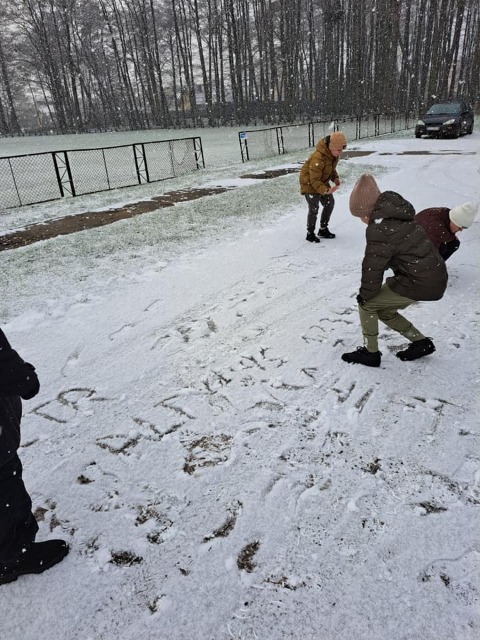 Uczniowie piszą pojęcia informatyczne na śniegu.