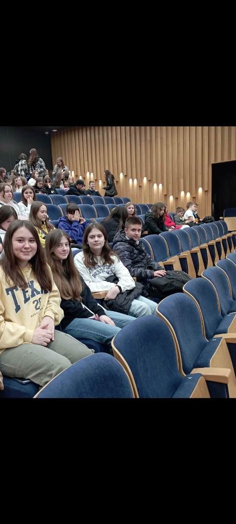 Na zdjęciu w auli Uniwersytetu Rzeszowskiego na tle innych uczestników spotkania siedzą uczniowie klasy siódmej SP w Dydni - trzy dziewczynki i jeden chłopiec.