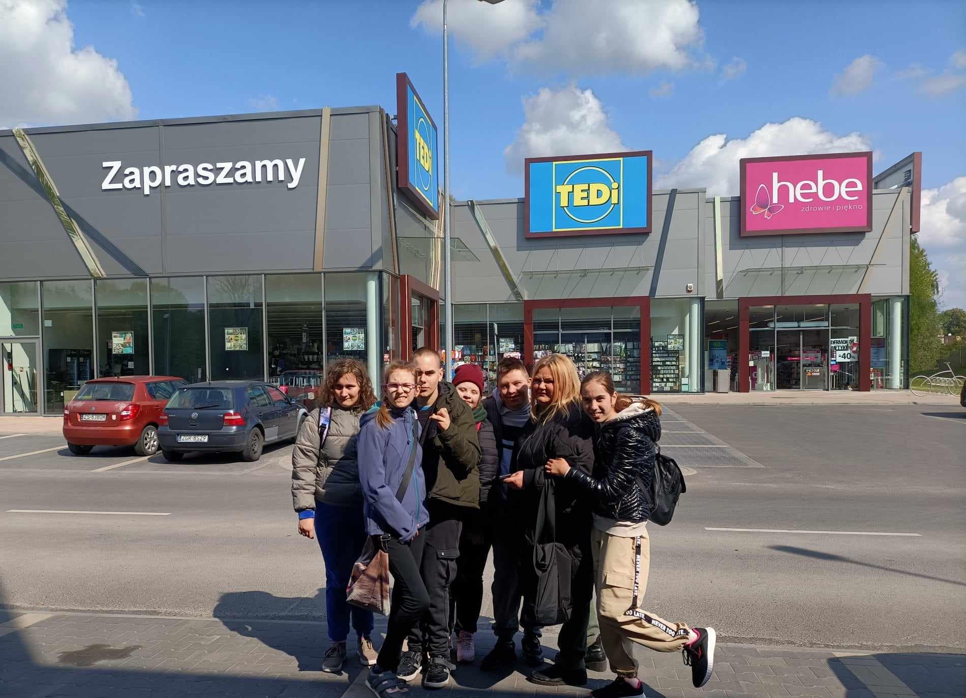 Uczniowie i pomysłodawczyni projektu Pani Agnieszka przed sklepami w pasażu handlowym na ulicy Łużyckiej.