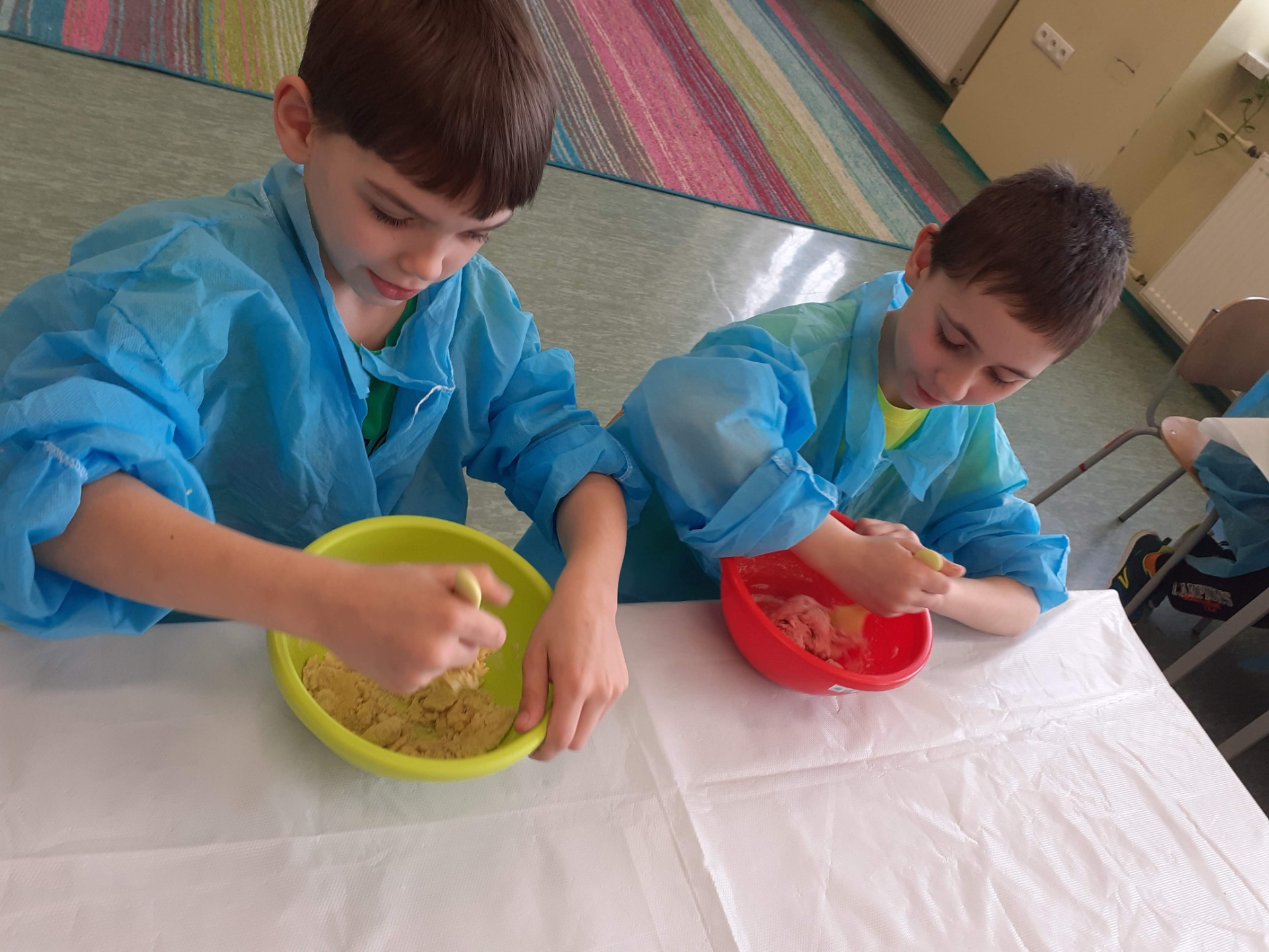 Dzieci siedzą przy stolikach i mieszają składniki masy solnej
