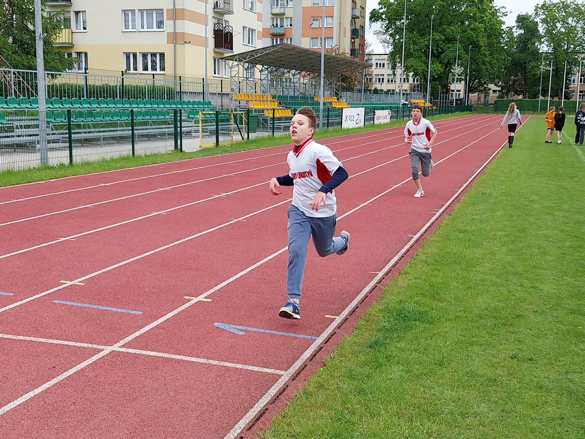 Chłopcy biegną na bieżni  na stadionie sportowym