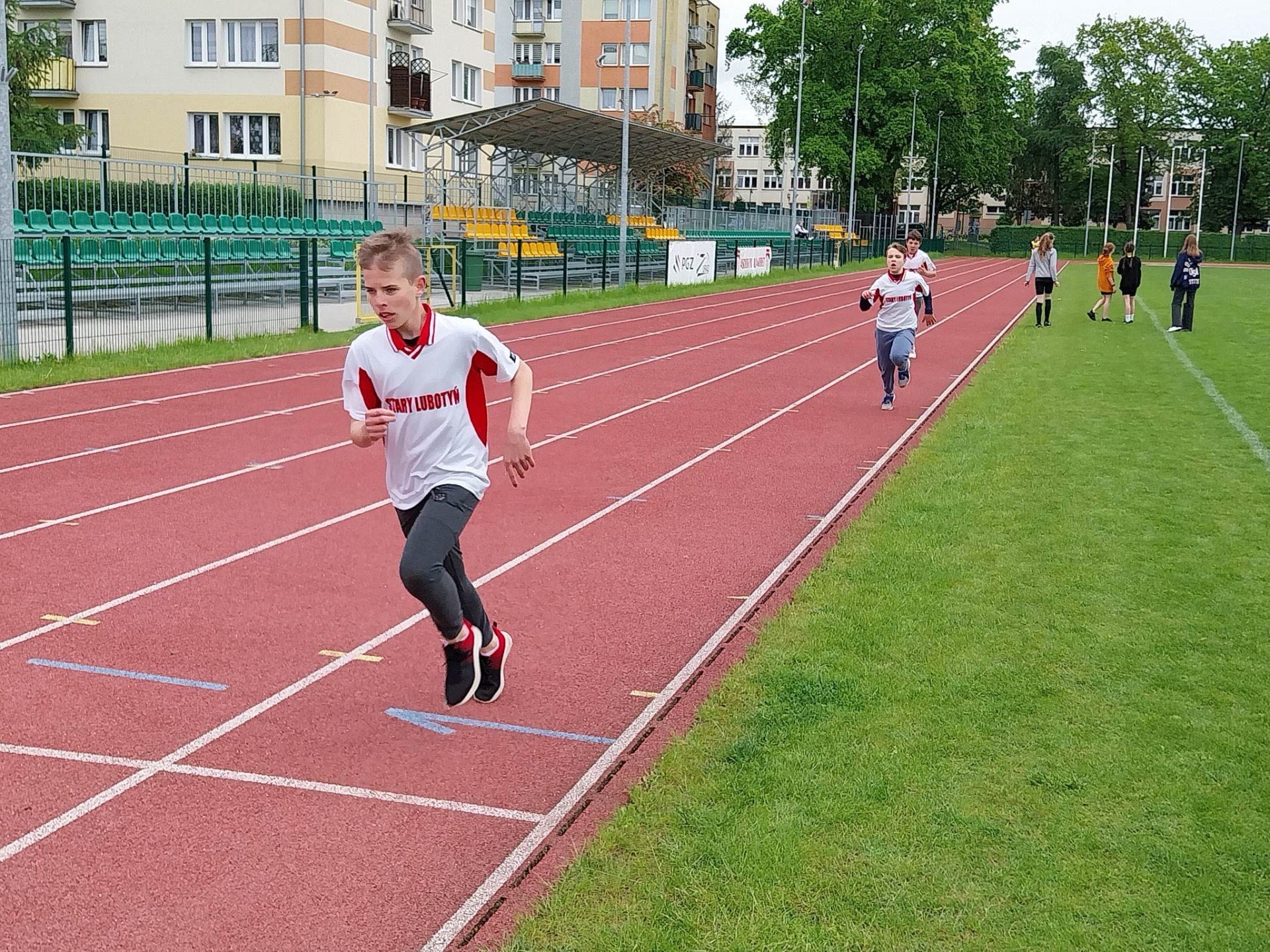 Chłopcy biegną na bieżni  na stadionie sportowym