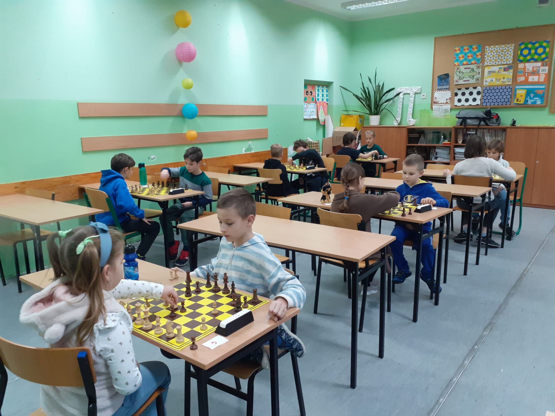 Uczniowie grają w szachy w sali szkolnej. 