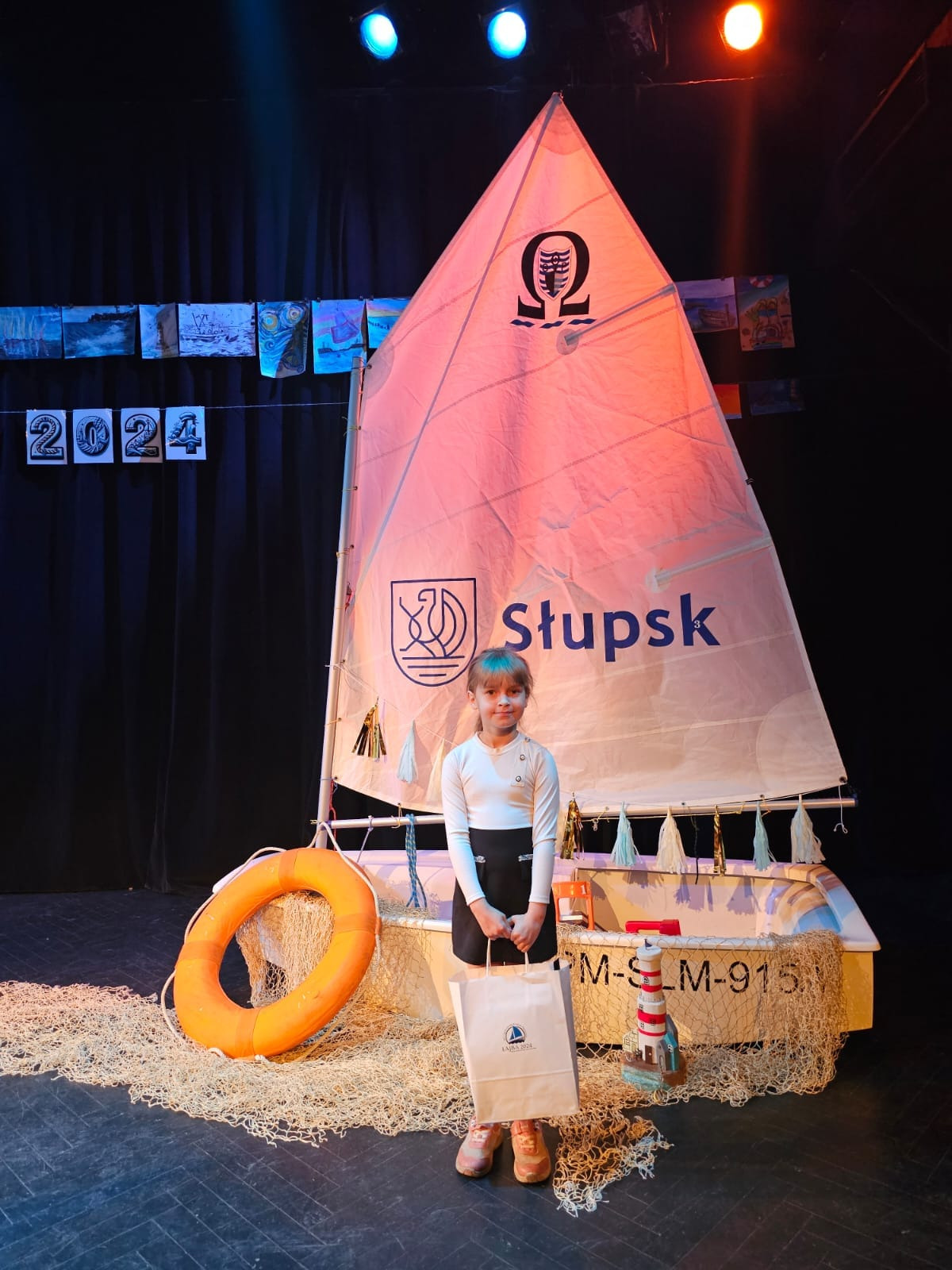 Laureatka konkursu plastycznego na tle instalacji okrętu podczas gali wręczenia nagród w konkursie ŁAJBA