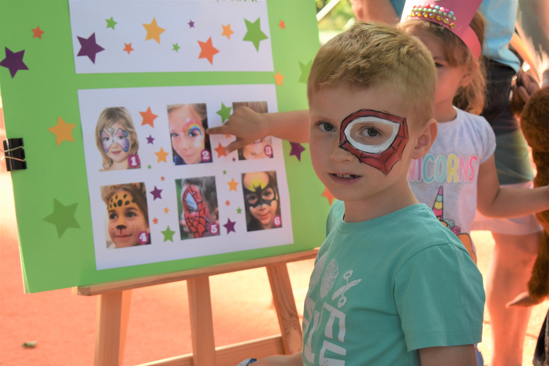 Chłopiec z pomalowaną twarzą zainspirowaną bajką spiderman.
